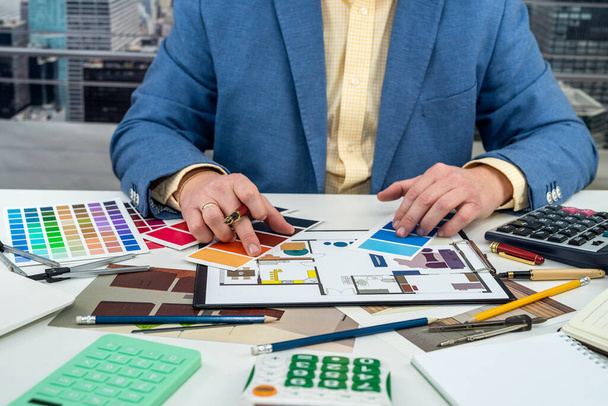Adam oda tasarımı için renkleri seçiyor. Ofisteki yaratıcı masasına renkli kumaş ve dizüstü bilgisayarlı modern daireler çiziyor. Tasmaları tasarımcının elleri alıyor. Tasarımcı bir erkek. - Fotoğraf, Görsel