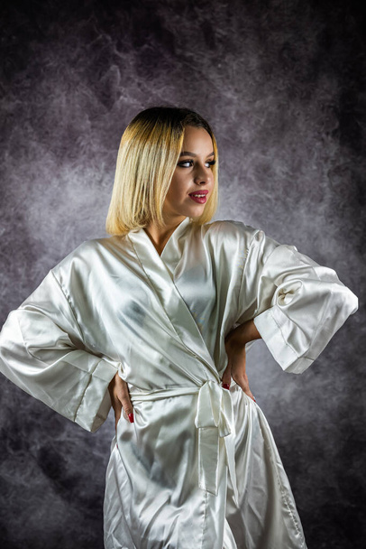 Сексуальная молодая женщина в светлом шелковом халате на обычном фоне. изолированный портрет женщины. - Фото, изображение