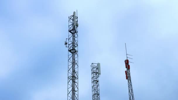 Anteny telefonii komórkowej wyróżniają się na tle błękitnego nieba z chmurami, upływ czasu - Materiał filmowy, wideo
