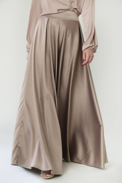 スタジオショットの女性ファッションモデルでベージュマキシサークルスカート、シンプルかつエレガントなシルクサテンフル長スカート - 写真・画像