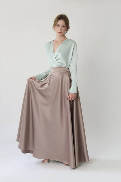 Studio shot of female fashion model in beige maxi circle skirt, Simplistic and elegant silk satin full length skirt - Foto, imagen