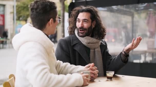 Медленное видео счастливой гей-пары разговаривающей и пьющей кофе на террасе кафетерия - Кадры, видео