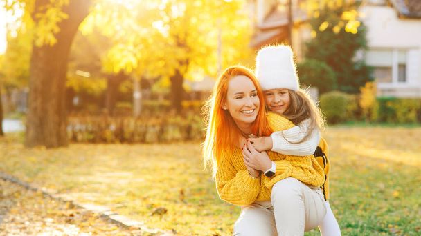 Mother and child daughter playing on autumn walk. Mom and girl laughing outdoors. Autumn fashion. Happy family in autumn park. - Foto, imagen