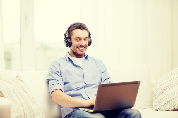 uśmiechnięty mężczyzna z laptopa i słuchawki w domu - Zdjęcie, obraz