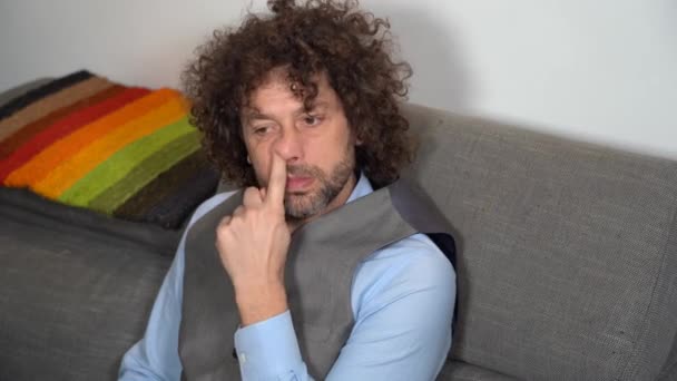 Uomo d'affari che scatta il naso a casa seduto sul divano in un momento di relax maleducazione e infantilismo in età adulta - Filmati, video