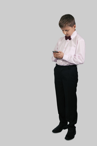 A boy on a gray background dials on your smartphone - Fotografie, Obrázek
