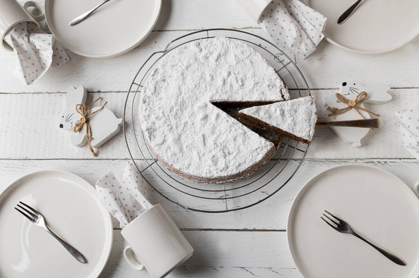 Laid sohvapöytä pääsiäiskauden herkullinen suklaa, manteli kakku, lautaset, kupit ja pääsiäispupu valkoisella pöydällä taustalla. Litteä - Valokuva, kuva