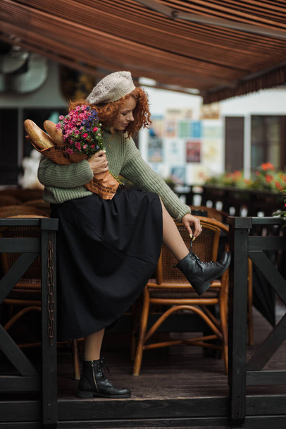 Retrato de mujer en un suéter boina con un ramo de flores del fondo del restaurante  - Foto, imagen