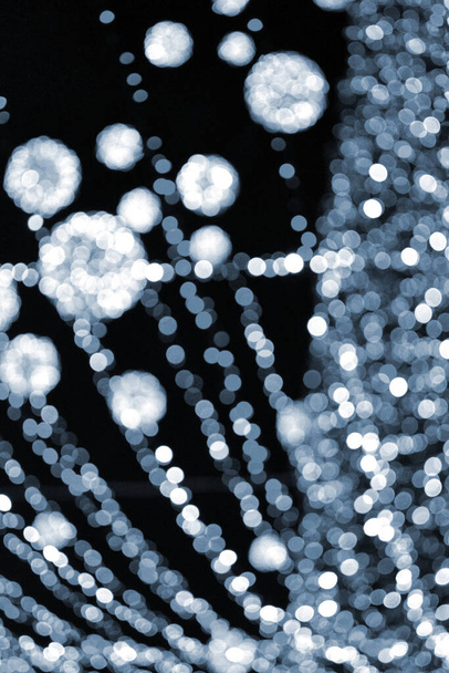 Fondo borroso. Hermosas guirnaldas luminosas y parpadeantes de Año Nuevo decoración de Navidad y bolas brillantes para el árbol de Navidad colgando al aire libre night.Blurry parpadeo bokeh spots fondo Color azul - Foto, Imagen