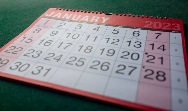 Naptár 2023, január, havi rendszerező. Nap, hónap, év, dátum és tevékenység szervező fal, asztali tervező. Piros, fehér naptár nagy betűkkel és számokkal, zöld háttérrel. Éles szögben lőttek.. - Fotó, kép