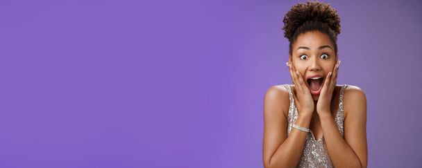 Nahaufnahme amüsiert überrascht attraktive afrikanisch-amerikanische junge Mädchen keuchend glücklich empfangen perfekte Geschenk Touch Wangen begeistert lächeln breit triumphierend gute Nachrichten feiern. - Foto, Bild