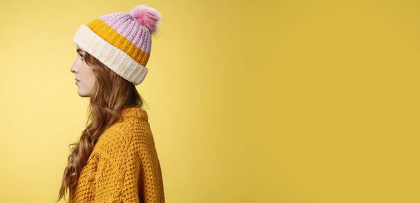 Profil strzał atrakcyjny kobieta kręcone fryzury noszenie kapelusz dzianiny sweter stojący kolejka zamówić ciepłe ciepłe napoje wygląd lewo normalny swobodny wyraz, pozowanie żółty tło studio. Przestrzeń kopiowania - Zdjęcie, obraz