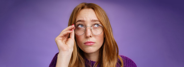 Életstílus. Ügyetlen és aranyos fiatal női tanár szemüvegben vörös haj néz bizonytalan és zavaros keres érdekelt a bal felső sarokban megható pereme szemüveg gondolkodás vagy képzelődés - Fotó, kép