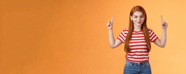 Cute lovely redhead girlfriend hint boyfriend what buy anniversary, pointing copy space promo, indicate fingers up, look camera assured, determined get what want, stand orange background. - Photo, Image