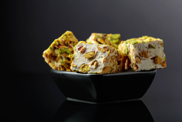 Traditional Turkish delight in a small black dish on a black reflective background. - Foto, imagen