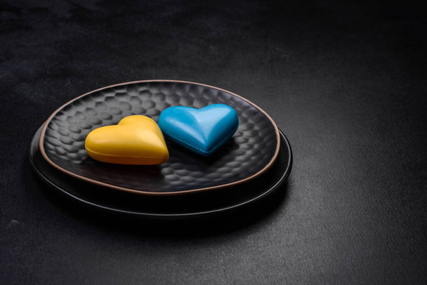 Chocolate hearts in the colors of the Ukrainian flag on a black ceramic plate. Valentine's day in Ukrainian colors - Foto, imagen
