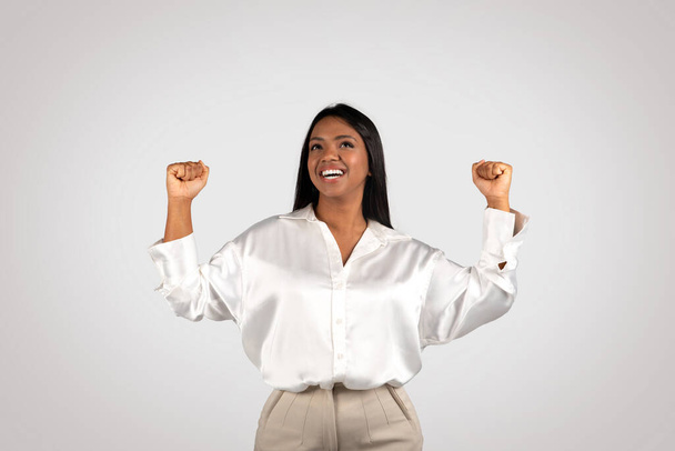 Gelukkige jonge Afro-Amerikaanse zakenvrouw maken succes en overwinning gebaar met handen geïsoleerd op witte achtergrond, studio. Geweldige baan, bedrijf en opstarten, geweldige oplossing en mensen emoties - Foto, afbeelding