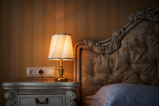Lampe sur une table de nuit à côté d'un lit
 - Photo, image