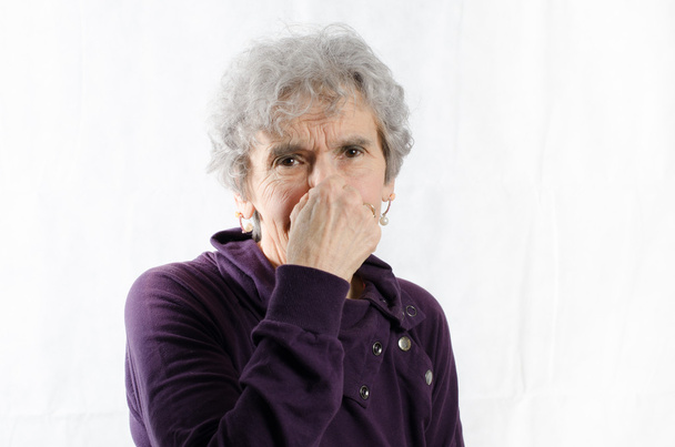 Oude vrouw houdt haar neus - Foto, afbeelding