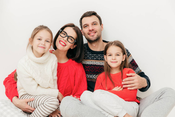 Familieportret: vader, moeder en twee zussen rechtstreeks in de camera kijken, hebben positieve expressies, omhelzen elkaar en vreugde, glimlach geïsoleerd op een witte achtergrond. Studio opname. Relatie - Foto, afbeelding