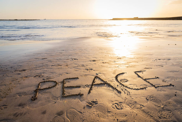 "日没の間にビーチで砂の上に書かれた平和:コピースペースと写真 - 写真・画像
