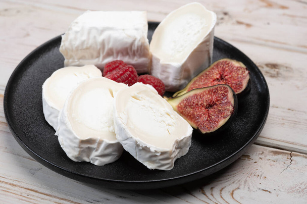 French organic matured white goat cheese with white mold close up served with fresh raspberries and figs - Photo, Image
