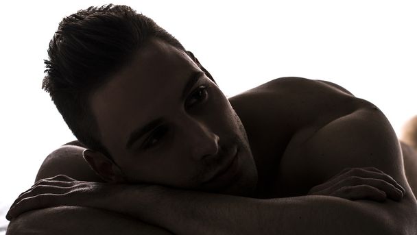 Chiaroscuro shot of cute young man naked resting - Foto, Bild
