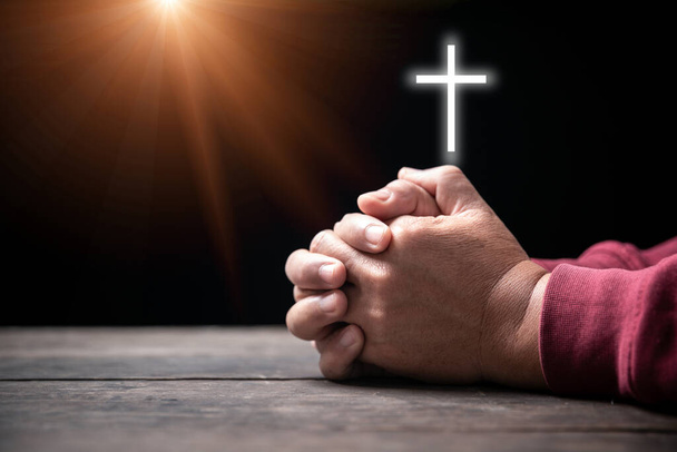 Χέρια διπλωμένα στην προσευχή στην Αγία Γραφή με σταυρό στην έννοια της εκκλησίας για την πίστη, την πνευματικότητα και τη θρησκεία, ο άνθρωπος προσεύχεται στην Αγία Γραφή με σταυρό το πρωί. Ο άνθρωπος χέρι με τη Βίβλο και rood προσεύχεται στο Θεό. - Φωτογραφία, εικόνα