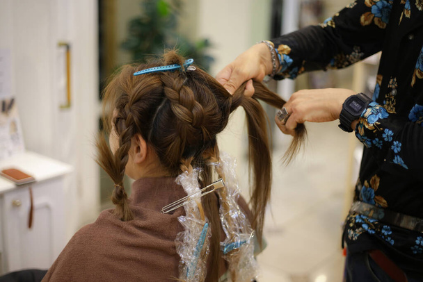 Мужчина-парикмахер, завязывающий женщине волосы - Фото, изображение