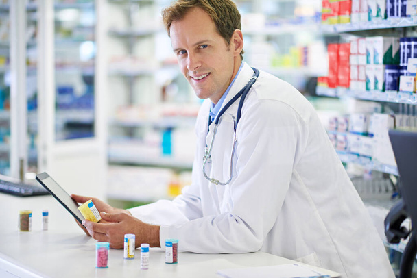No one knows where I get all my information from...A pharmacist working on a digital tablet - Foto, imagen