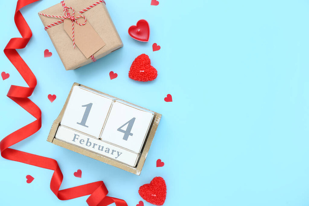 Кубический календарь с датой 14 февраля, подарок, лента и свечи на синем фоне - Фото, изображение