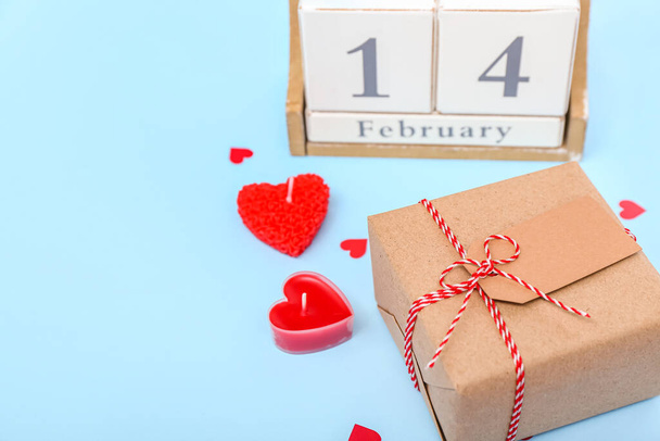 Кубический календарь с датой 14 февраля, подарок и свечи на синем фоне, крупный план - Фото, изображение