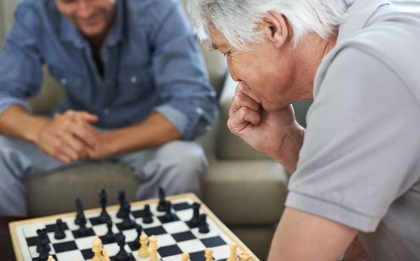 Обдумывает свой ход. отец и сын играют в шахматы вместе дома - Фото, изображение