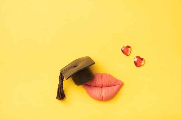 Губы с дипломированной шапкой и маленькими сердцами. Концепция образования в отношениях. - Фото, изображение