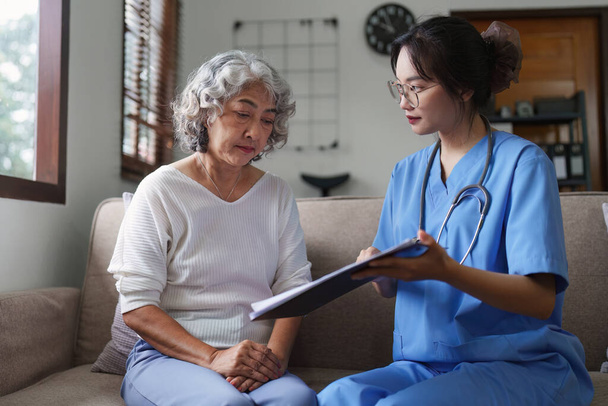 Aasialainen nuorekas sairaanhoitaja hoitaa potilaita tai vanhuksia kotona. hoitotyö kotona käsite. - Valokuva, kuva