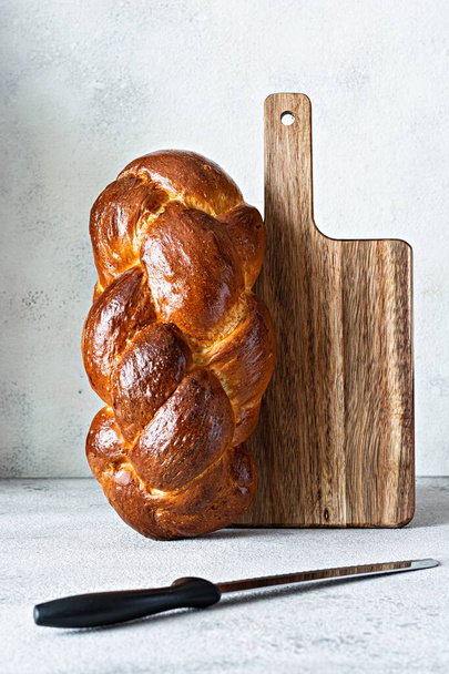Το Challah ή Hala είναι ένα παραδοσιακό εβραϊκό γλυκό φρέσκο σάββατο Πλέξιμο ψωμί (καρβέλι), φρέσκο ψωμάκι με επικάλυψη σε ξύλο κοπής. Brioche στο τραπέζι του πρωινού.  - Φωτογραφία, εικόνα