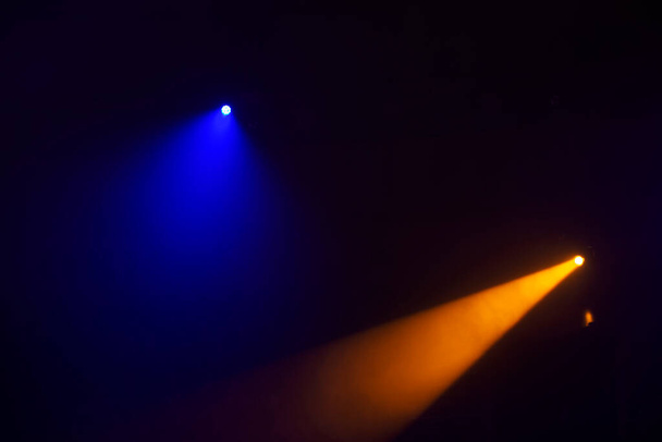 Πορτοκαλί δέσμες φωτός από προβολείς σκηνής σε σκούρο μπλε φόντο.Φωτισμός της σκηνής. - Φωτογραφία, εικόνα