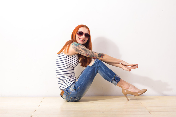 Laughing beautiful redhead woman with sunglasses sitting on the floor and posing - Foto, Imagen