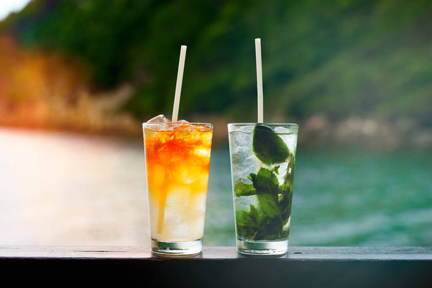 Glasses of Mai Tai and Mojito cocktails on the beach. - Photo, image