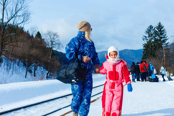Μητέρα και κόρη φοράνε στολές σκι κοντά στο σιδηρόδρομο. - Φωτογραφία, εικόνα