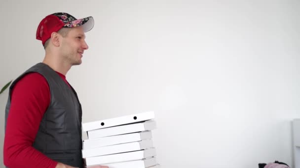 Pizza teslimatı Kurye beyaz arka planda beyaz karton pizza kutusunu geçiyor. - Video, Çekim