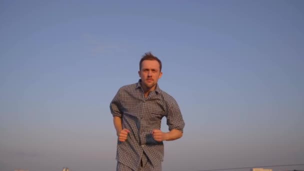 Baard Kaukasische man in nachtkleding loopt outdoor kijken vooruit. Ochtend oefening concept. Heldere blauwe lucht op de achtergrond. Hoge kwaliteit 4k videobeelden - Video