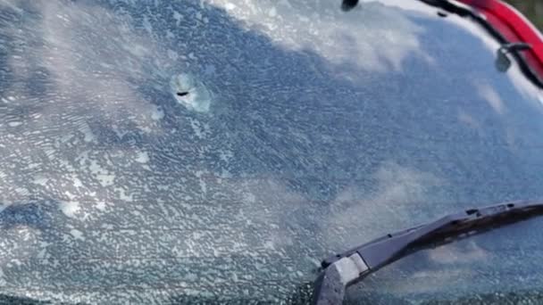 車のフロントガラスに弾丸の穴。自動車保険。民間人の車,壊れたフロントガラスと,シールによって損傷を受けました.ウクライナの領土のロシアの本格的な侵略の犠牲者 - 映像、動画
