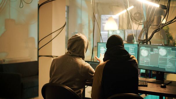 Anonimowi ludzie pracujący razem, by złamać system sieciowy na komputerze, kradnąc informacje i hasła. Osoby sadzące wirusa i zajmujące się phishingiem dla ransomware, cybernękania lub molestowania. - Zdjęcie, obraz