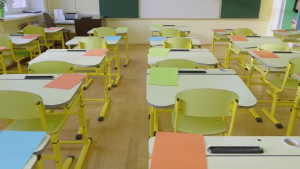 Escola sala de aula vazia com quadro-negro branco e verde, mesas amarelas educacionais e cadeiras para estudar aulas do ensino fundamental. Interior da educação infantil, conceito educacional para crianças - Filmagem, Vídeo