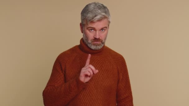 I am dont want it, not me. Confused displeased senior mature man in sweater pointing fingers herself, rejection, refusal, stop failure sign. Pretty middle-aged guy isolated on beige studio background - Imágenes, Vídeo