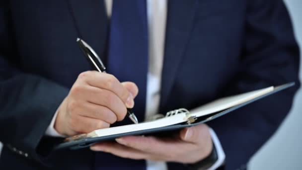 Hands of a businessman writing a schedule or recording ideas in a diary - Footage, Video