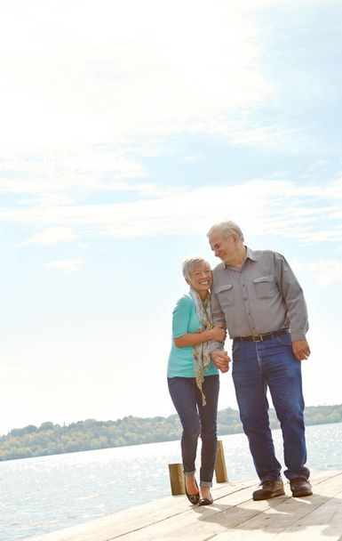 Fühlen sich wieder wie Teenager. Ein älteres Ehepaar spaziert am Steg entlang - Foto, Bild