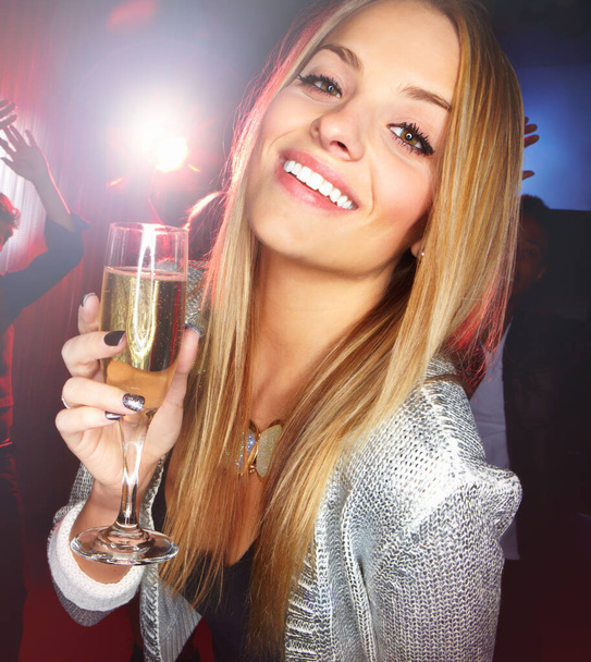 乾杯！。ダンスフロアにワインのグラスを持って立っている間、カメラに笑みを浮かべて美しい若いブロンドの女性 - 写真・画像
