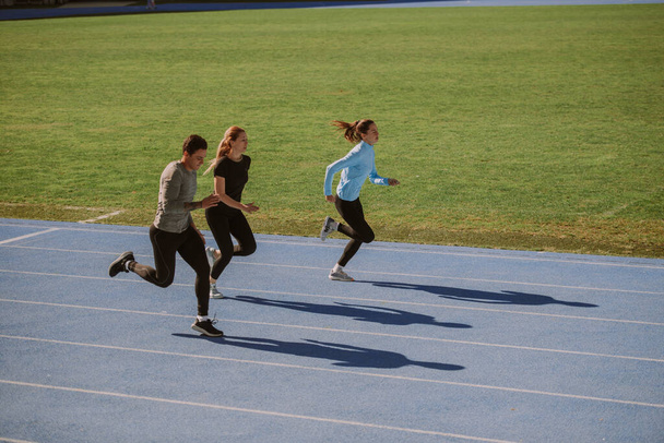 1人の男性と2人の女性が空のスタジアムでジョギングしている。次のマラソンに向けて準備中です。 - 写真・画像